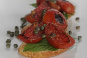 grilled tomato and capers on crostinie with basil